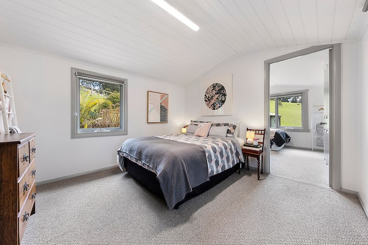 Queen bedroom view 1: Spacious room with windows on 2 sides of the room and French doors to the courtyard. Access to the king singles room can be seen in this photo