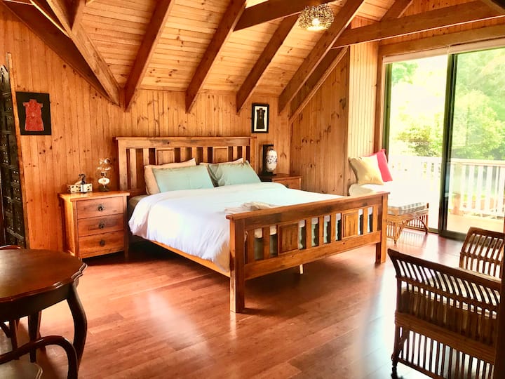 La suite principal de arriba (nuestra favorita) (nuestra favorita) con cama tamaño king, baño completo, esquina de estudio y balcón privado con vistas al mar y al jardín.