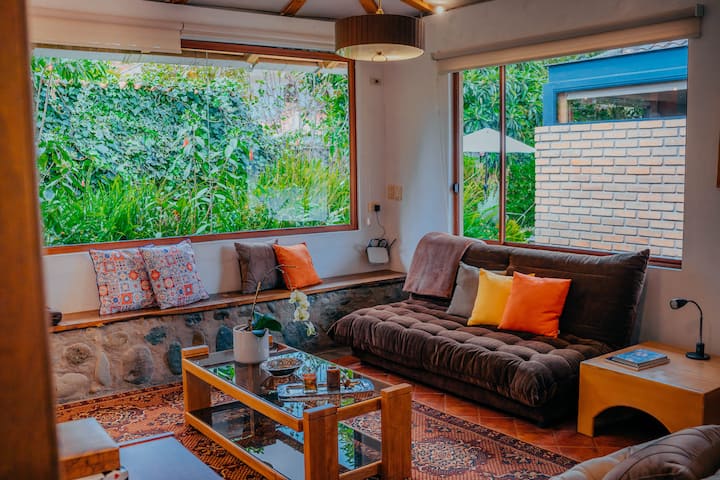 "Soggiorno luminoso e confortevole con divano di design e vista sul paesaggio montuoso. Perfetto per rilassarsi dopo una giornata di visite turistiche."