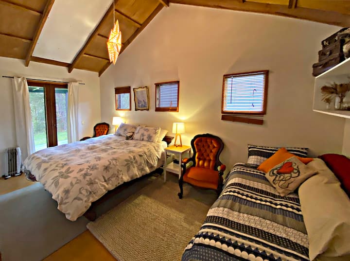2nd bedroom features French doors that open out onto east facing deck with views of the temperate rainforest trees.