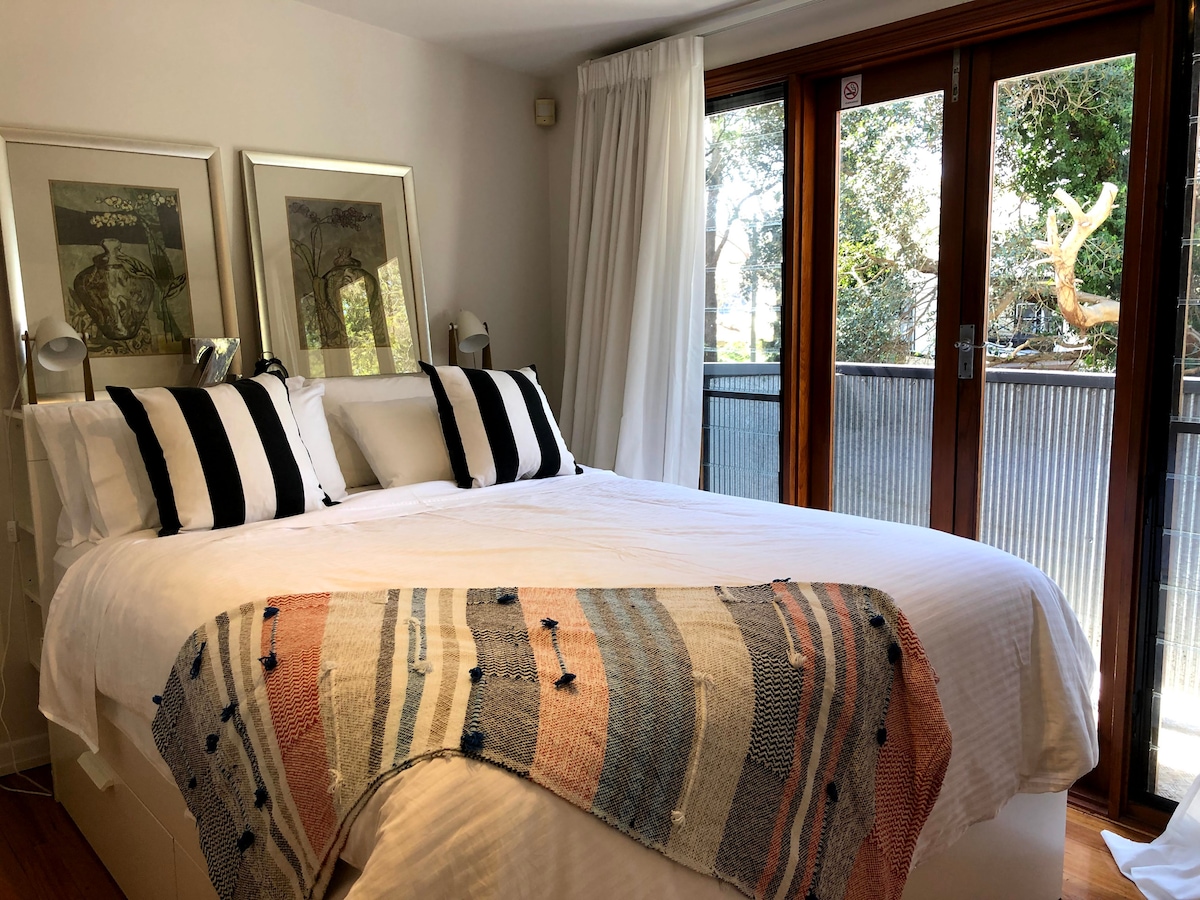 Una vista frondosa desde tu dormitorio principal de arriba con una cómoda cama tamaño queen de lujo.