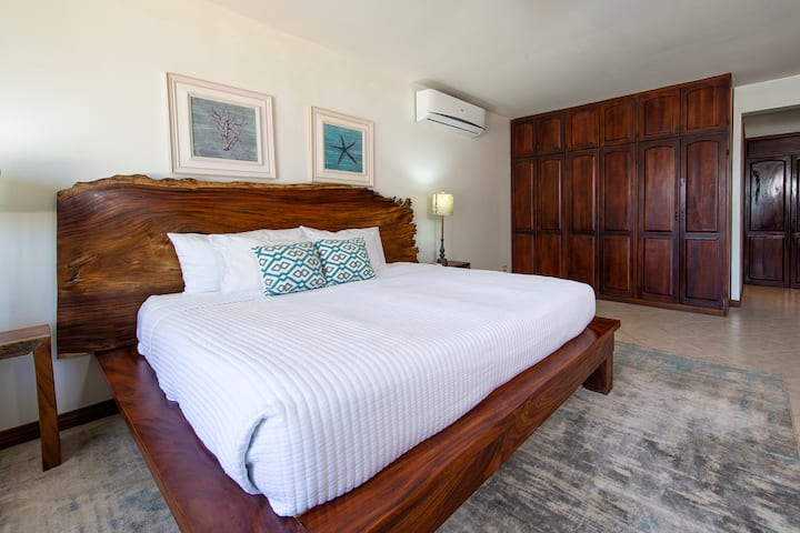 ห้องนอนใหญ่ชั้นบนพร้อมทีวีเครื่องปรับอากาศและห้องน้ำในตัว  วิวชานบ้านและอ่าว  