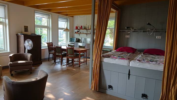 Cama tamaño king con cortinas para separar la cama del estudio. Debajo de la cama, el espacio de almacenamiento para la cama tamaño queen.