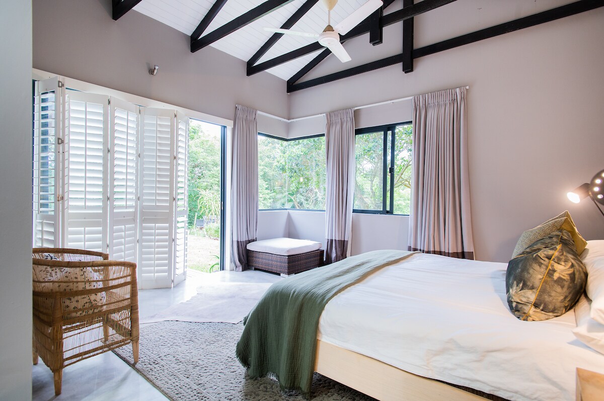 Dormitorio principal con cama tamaño king XL y hermosas vistas a los arbustos