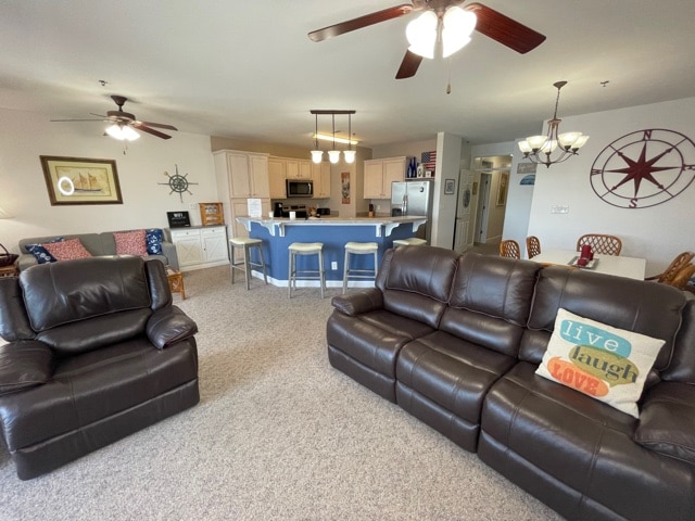A spacious living area features two dark leather recliners, a cozy sofa, and a dining area with a large table set for eight. The open kitchen is visible in the background, showcasing modern appliances and a central island with seating.