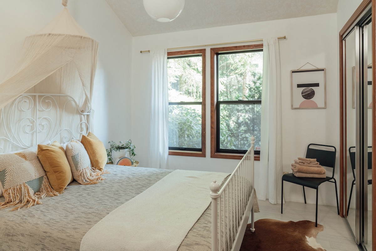 1 of 2 main level bedrooms, featuring a queen size bed and vaulted ceilings