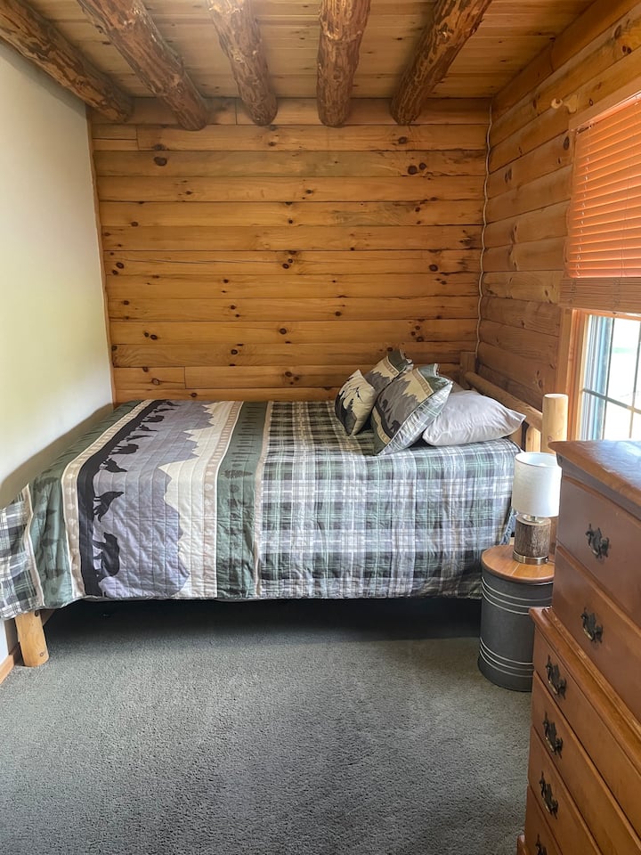 Cama tamaño queen en el primer piso con un colchón doble almacenado debajo.