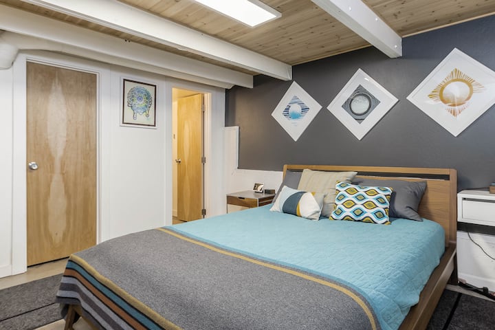 Downstairs bedroom with queen size bed with luxury bedding, Google nest hub, direct access to bathroom and backyard. 