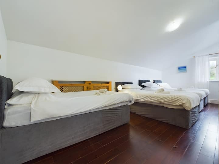 Quatro camas de solteiro em um quarto leve e arejado com vista para o pomar, localizado no primeiro andar com roupeiros embutidos.