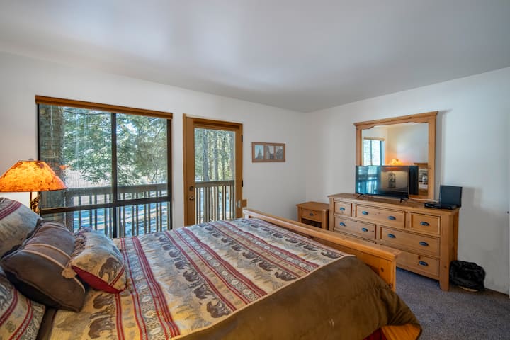 Основната спалня разполага с двойно легло, достъп до балкон и изобилие от естествена светлина, създавайки спокойно място за отдих с акцент, вдъхновен от планината, и телевизор за пълноценен отдих.