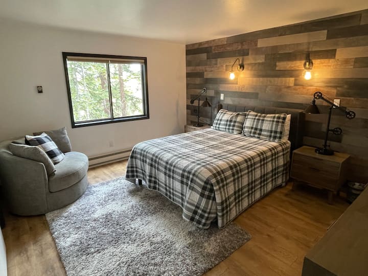 Uvoľnite sa v tejto hlavnej spálni s manželskou posteľou, modernizovaným osvetlením a krásnymi stenovými prvkami z recyklovaného dreva. Užite si prirodzené svetlo z veľkého okna a pohodlie vlastnej kúpeľne!