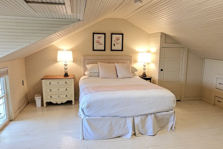 تقع غرفة النوم 3 التي تحتوي على سرير بحجم كوين على درج، مع نوافذ تطل على أسطح المنازل في حي لوري هيل.