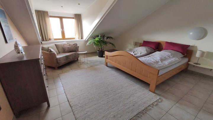 Bedroom with double bed and reading corner with small sofa