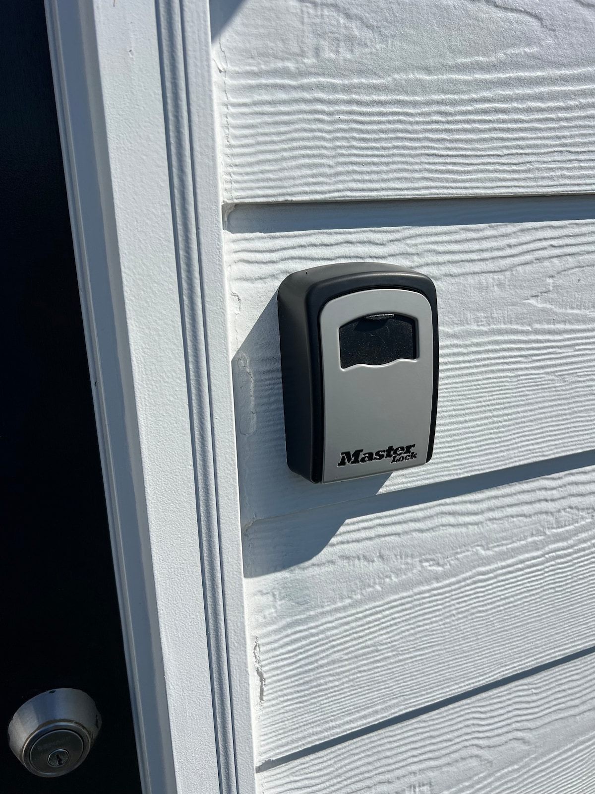 A black push button key pad is mounted next to a white door. The key pad features a clear digital display and is designed for entry access, providing a secure entry point for guests.