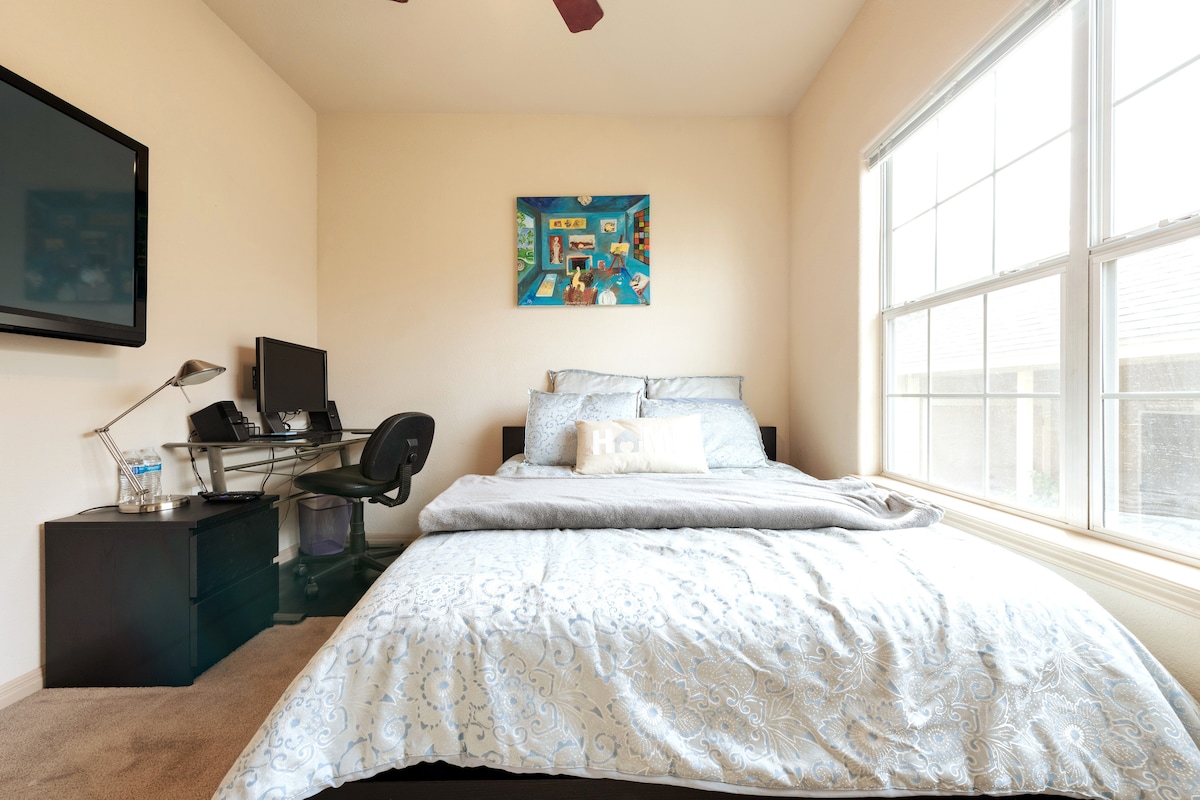 Vista alternativa de tu dormitorio con colchón Tempurpedic tamaño queen, TV de plasma de 50pulgadas,  Roku Express, escritorio de trabajo con monitor de 24 pulgadas y más.