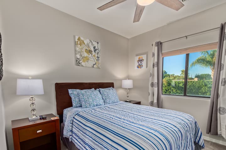 Spálňa pre hostí na poschodí s manželskou posteľou Queen a televízorom na stene. 