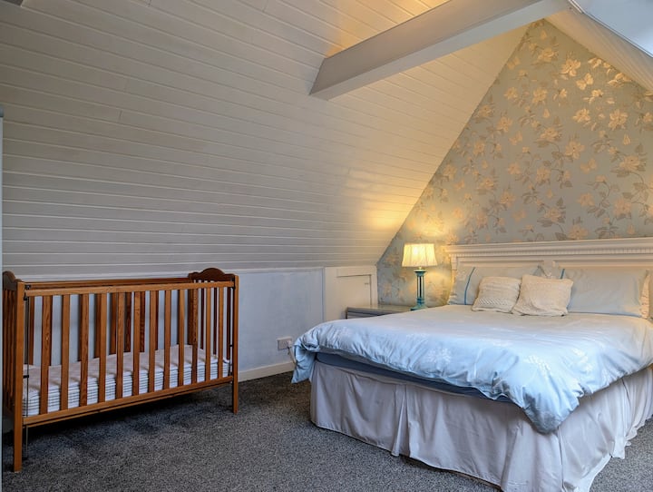 An upstairs large double bedroom with en-suite shower and cot if required.