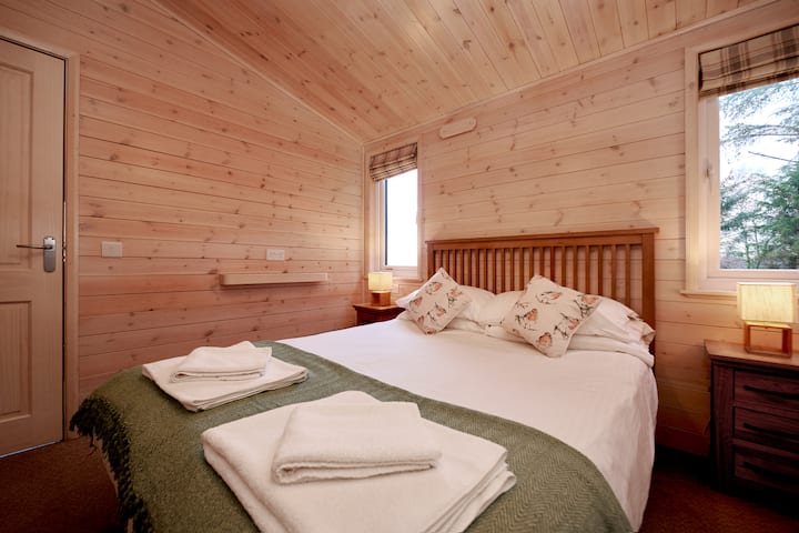 The master bedroom at Ben Klibreck Lodge. This comfortable double room has an en-suit shower room and built in wardrobes.
A wooden cabin with hot tub. 2 Bed-room (sleeps 4). Burgie woodland lodges.