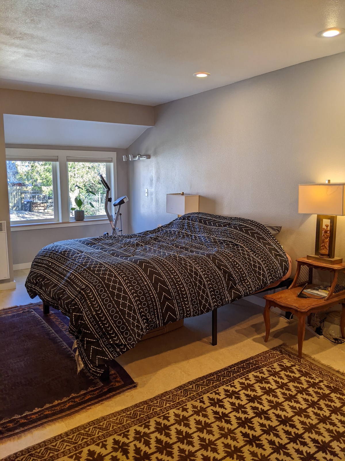 Pumzika katika chumba kikuu cha kulala. Mlango na madirisha hutoa ufikiaji wa moja kwa moja kwa ua wa nyuma. 