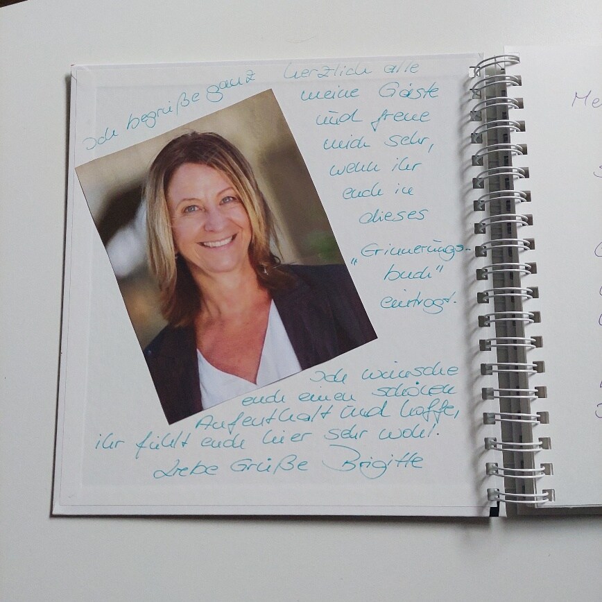 An open scrapbook page displays a portrait photograph in the center, surrounded by handwritten notes in blue ink. The layout appears personal and inviting, with a soft, neutral background enhancing the overall presentation.