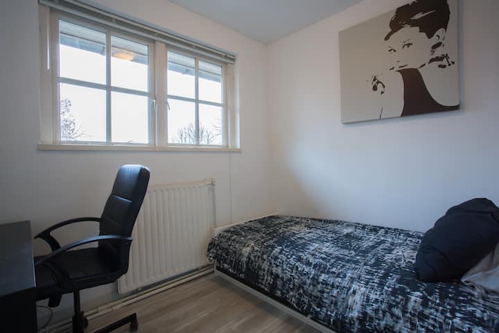 Chambre n °4 : un lit simple, des étagères, des cintres et un bureau avec chaise.  