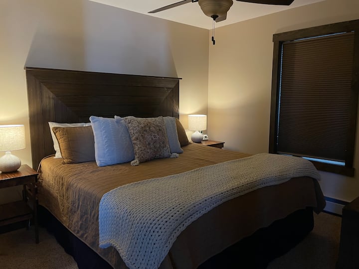 Main-level king bedroom with a custom headboard.  Room includes dresser, large closet, and mounted TV.