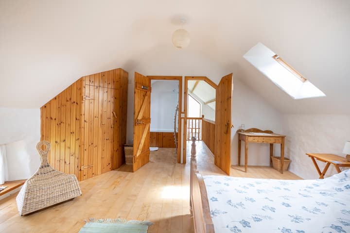 The upstairs bedroom is bright and clean. With views of the Pembrokeshire countryside, a large comfy queen bed, en suite bathroom, and exquisite handcrafted details.