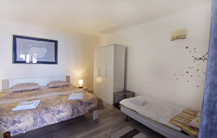 Área para dormir con una cama doble, sofá cama para una persona, armario, mesita de noche