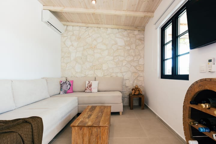 The living room boasts a corner sofa, A/C and a 42’’ HDTV.