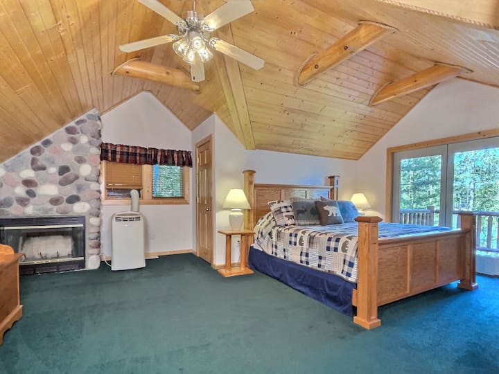 Dormitorio principal con balcón y cama tamaño king.  Solo la fuente de aire acondicionado de esta habitación es el aire acondicionado de la ventana.  La chimenea de leña no es para uso del inquilino.
