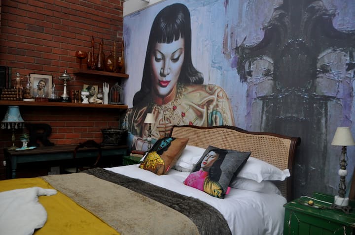 A Saffron bedspread accentuated with pillow prints of Tretchikoff's Miss Wong and Chinese Girl compel attention 
