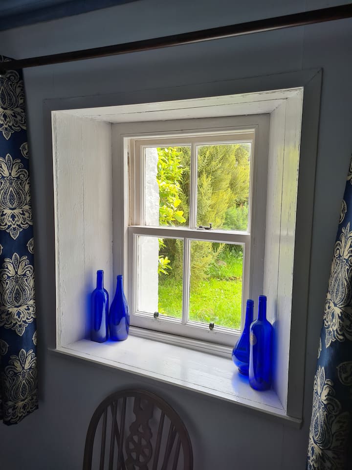 We have retained most of the cottage's period features such as the original thick stone walls in the central part of the house, the wooden floorboards and latched doors, and these old sash windows with deep sills.