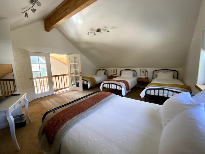 Loft recintato con un letto matrimoniale e 3 letti singoli. Un grande spazio privato per rilassarsi su una moquette pulita. 