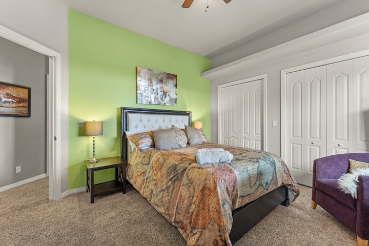 חדר שינה עם מיטת קווין סייז, שידה, כורסה ונוף לפטיו עם הג'קוזי ולפסגות ההרים 