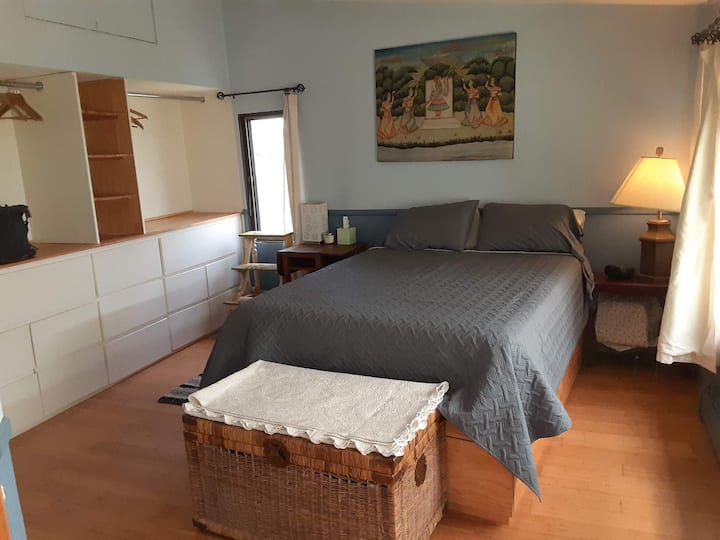 Dormitorio azul con cama tamaño queen, espacio para colgar y escritorio. Este dormitorio tiene una puerta cerrada con llave que conduce a un espacio de almacenamiento sin terminar.  El espacio sin terminar está fuera del alcance de los huéspedes.