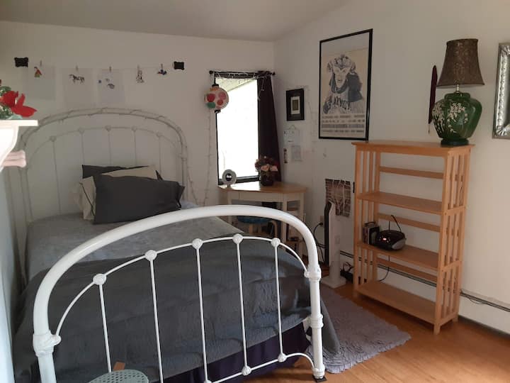 Dormitorio morado: cama matrimonial con espacio para colgar y pequeño escritorio, estantería.
