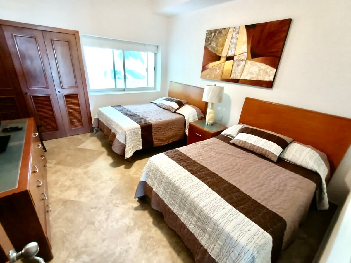 ห้องนอน 2 มีทีวีตู้เสื้อผ้าและเตียงควีนไซส์ 2 เตียง