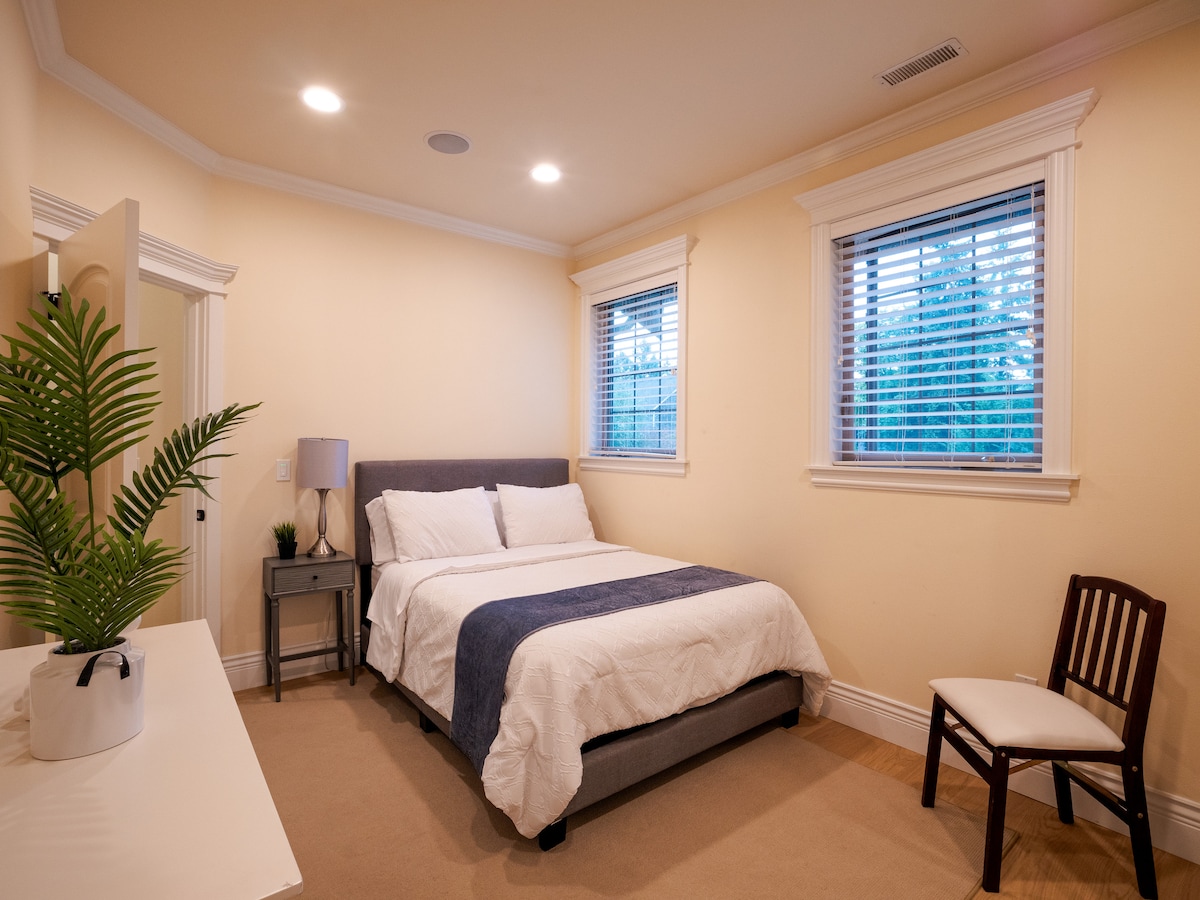 Изглед към спалнята за гости отзад вляво. Два големи прозореца, за да внесете естествена светлина в уютната си спалня за гости.