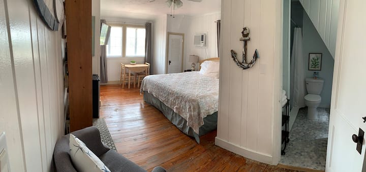 View from entrance of Bayside Bliss, an upstairs room with king bed, private bathroom with walk-in shower. Includes coffee maker, microwave, and mini-refrigerator/freezer