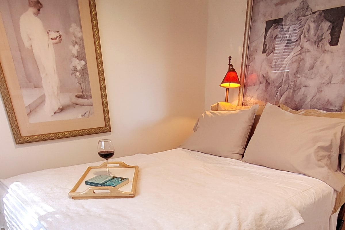 מיטת קווין סייז נוחה עם שמיכת משי ומבחר כריות רכות ומוצקות. וילונות האפלה ותריסים שומרים על האור לשינה נינוחה.