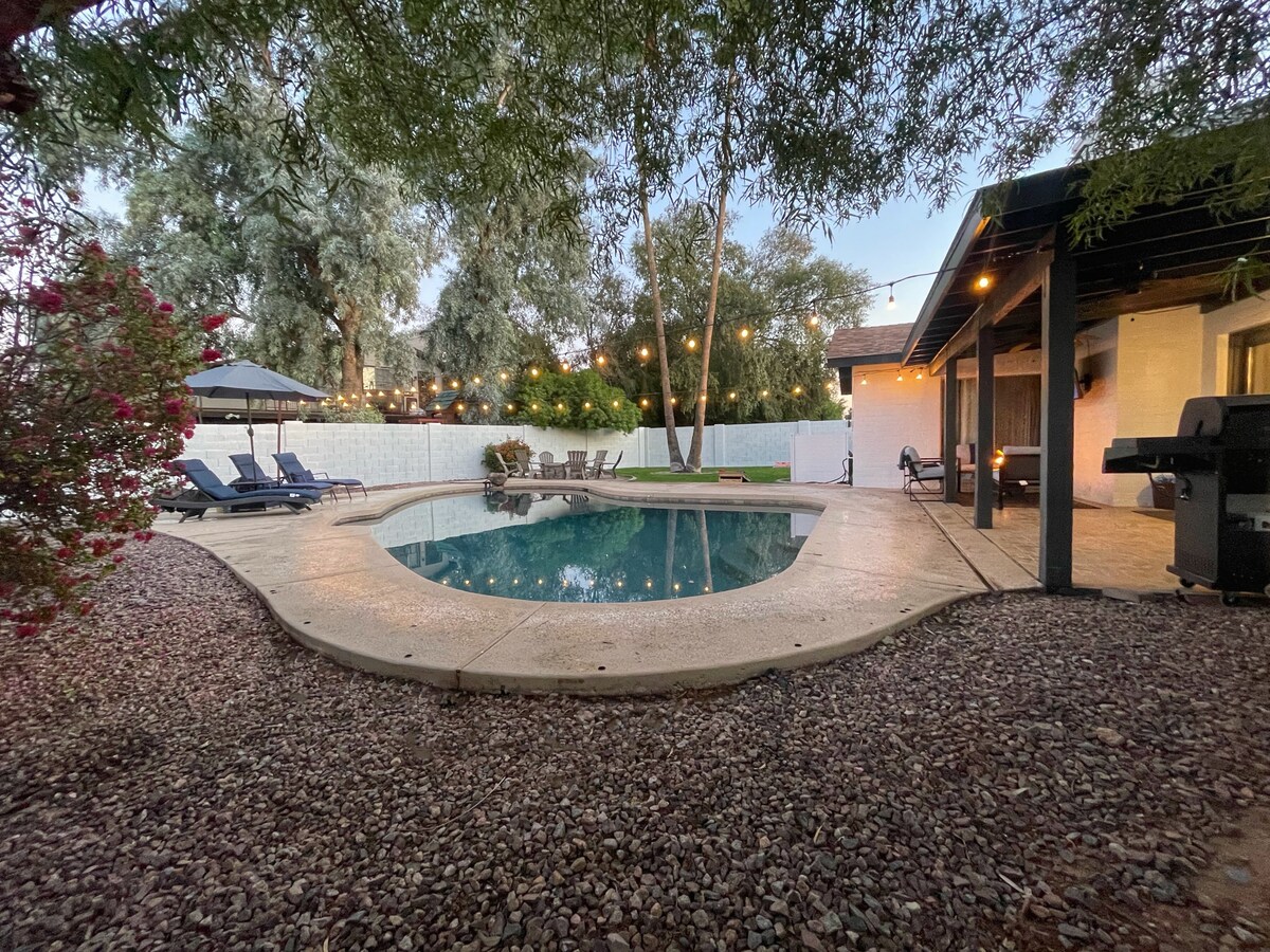 The outdoor space features a diving pool surrounded by natural stone and a patio area. Comfortable lounge chairs are arranged beside the pool, with ambient lights strung overhead. A gas BBQ grill is positioned nearby, enhancing the outdoor dining experience.