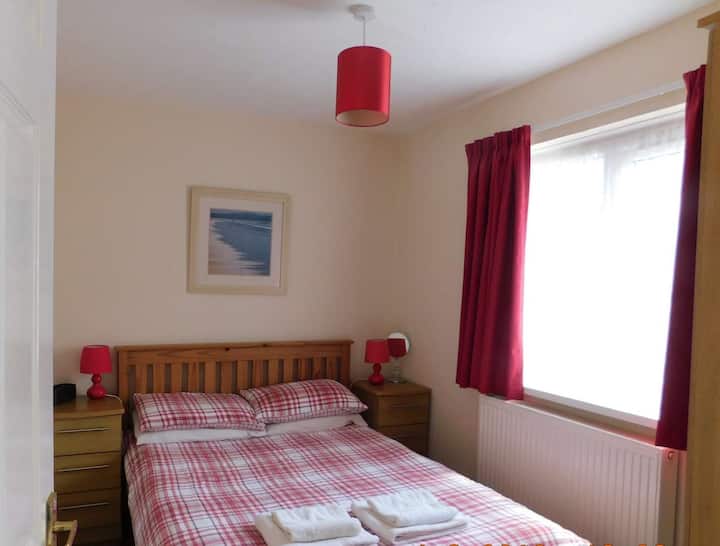 חדר שינה זוגי עם מלתחה בגובה מלא, שני ארונות ליד המיטה עם מנורות קריאה בודדות, מראה ורדיו שעון עם נקודות USB לטעינת טלפונים וטאבלטים.
נוף לגינה הקדמית.