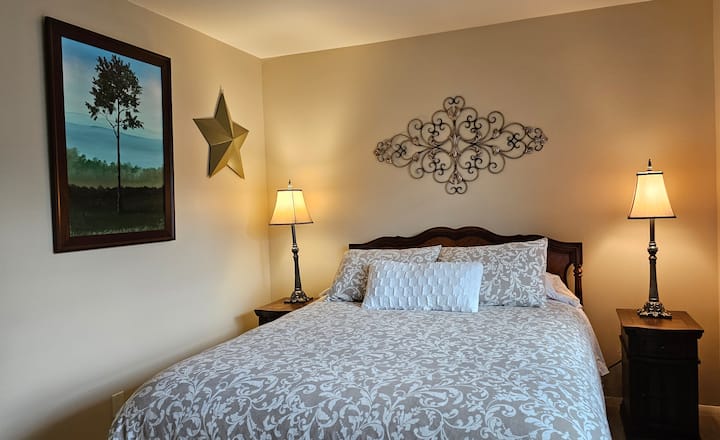 Second bedroom with queen bed, matching bedside stands with USB chargers, bedside lamps, clock with phone charging pad, full size dresser and closet space available for guest use.