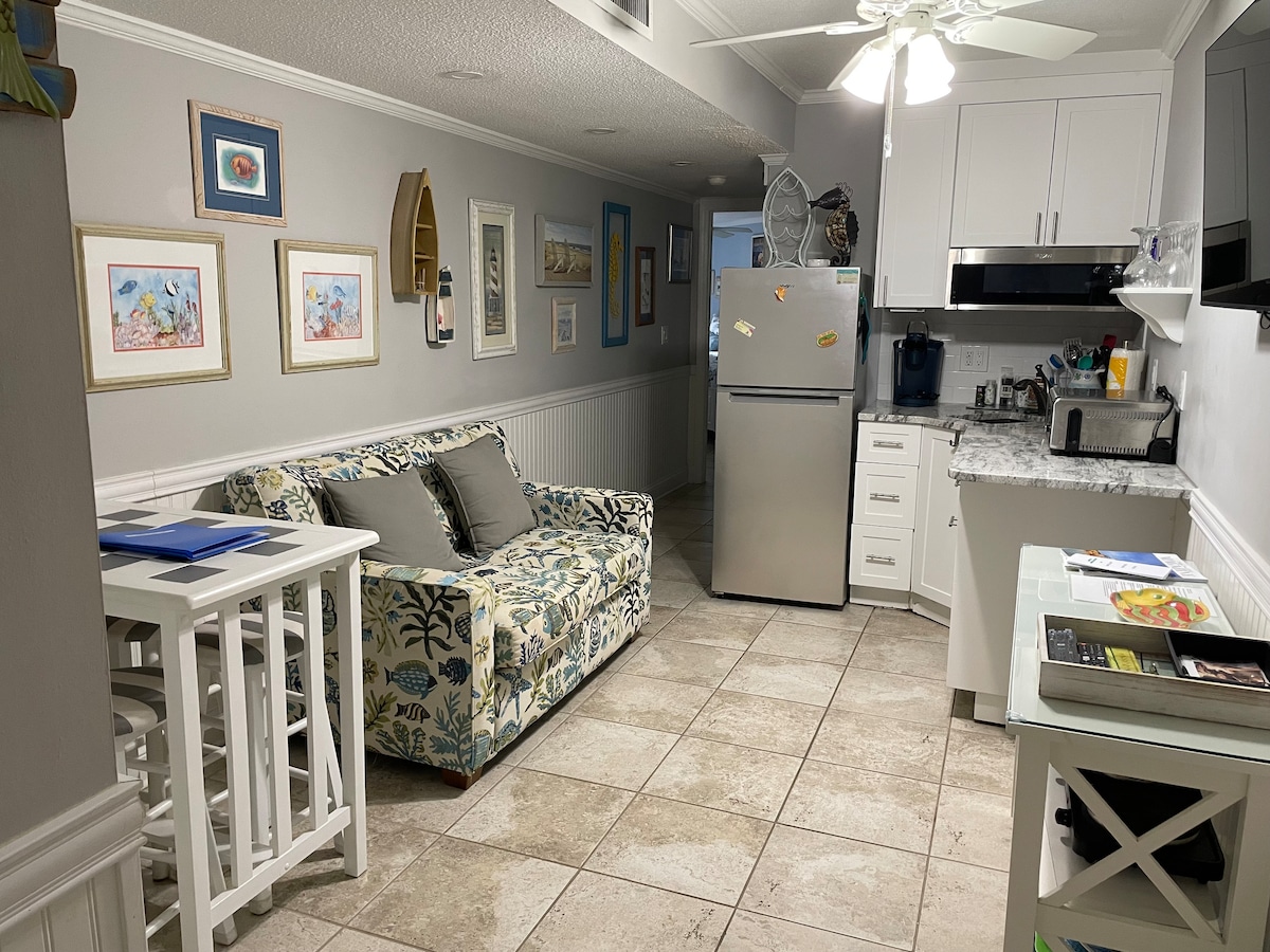 Área de estudio y cocina pequeña con refrigerador de tamaño normal y máquina de hielo, cafetera Keurig, horno tostador con freidora de aire