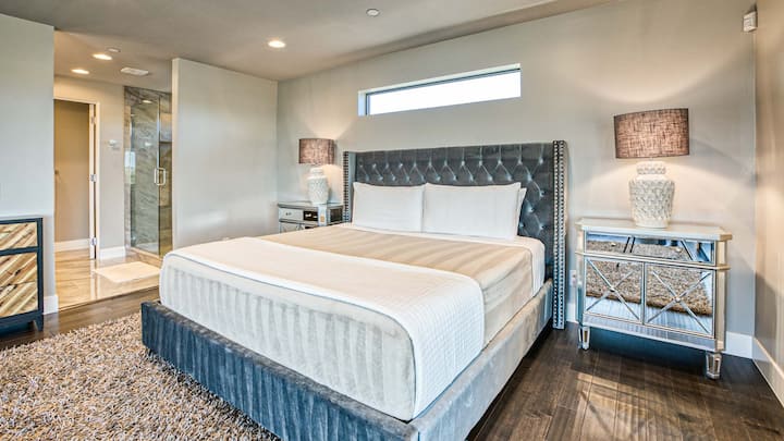 Elegante dormitorio con cama tamaño king, mesitas de noche con espejos, lujosa alfombra y un elegante baño privado