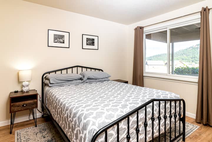 חדר שינה קווין למטה עם אזור ארון ואחסון בקיר. שני שולחנות צדדיים עם שקעי חשמל נגישים נמצאים בכל אחד מצידי המיטה.