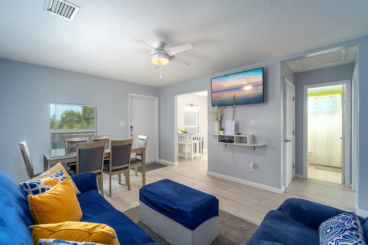 ห้องนั่งเล่นแบบเปิดโล่งและพื้นที่รับประทานอาหารพร้อมสมาร์ททีวีและโซฟาเบดควีนไซส์