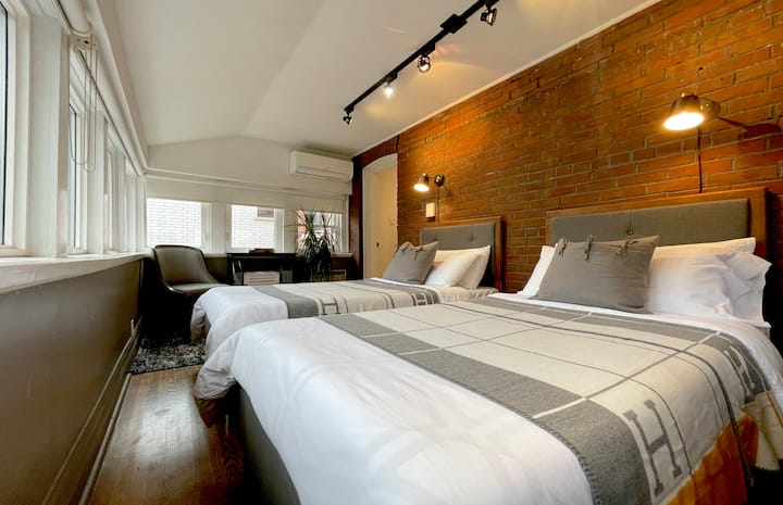 The Brick House Bedroom (2nd floor) Large Bedroom with two single beds (can be pushed together to make a king size bed), heritage exposed brick wall, hanging closet, Smart TV, desk, wrap-around windows with incredible terrace and back garden view.