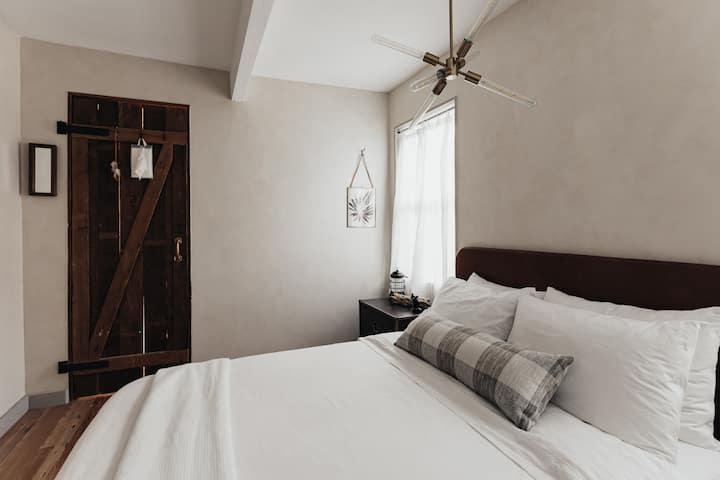 Táto veľká posteľ a útulná spálňa majú minimálnu blaženosť. Nočné komody v štýle kampane a malá skriňa s policami a vešiakmi vás udrží v usporiadaní a pohodlí.