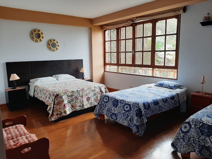 Dormitorio primer piso. Baño completo independiente, 1 cama de 2 plazas y 2 camas de plaza y media. Vista al jardín delantero.